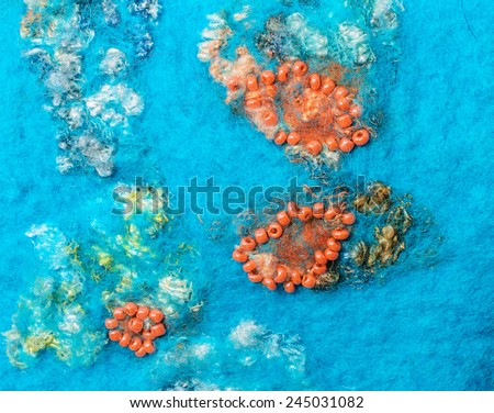 Turquoise fabric texture of wool and string of orange beads and lace.  Craft background