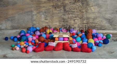 multicolored felted beads, wooden chest and red boots on the wooden background