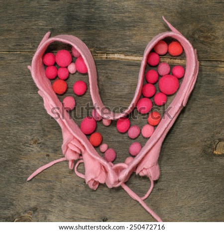 pink belt with heart-shaped  and felted beads on the wooden background