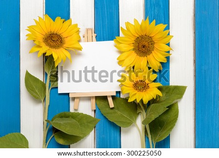 Three ornamental sunflowers and easel on the background of colored wooden boards