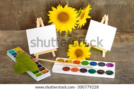 sunflowers, painting and easel on the wooden background