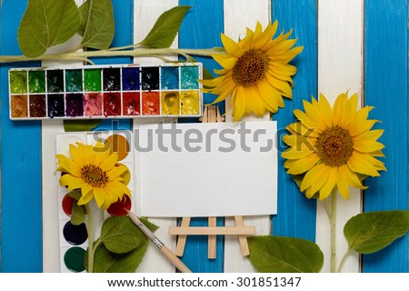 sunflowers, painting and easel on the background of colored wooden boards