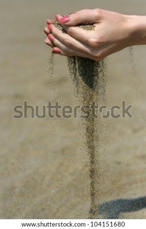 Sand is falling from the girl's hands