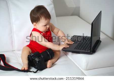 Baby is playing with laptop and camera