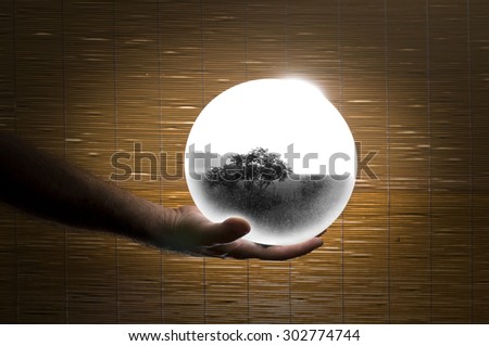 Human Hand Holding a White Globe with Double Exposed Monochrome Landscape