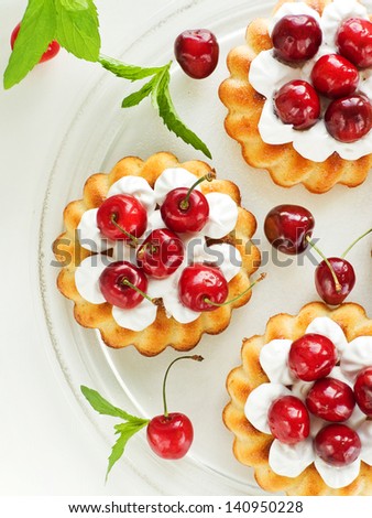 Coconut cakes with whipped cream and sweet cherry. Viewed from above.