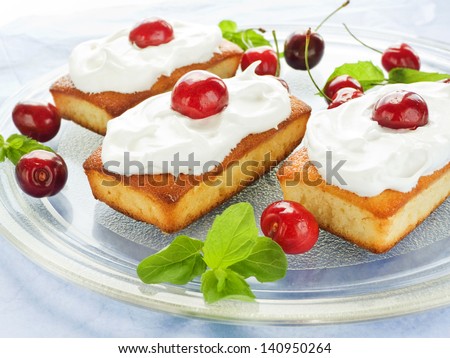 Coconut cakes with whipped cream and sweet cherry. Shallow dof.