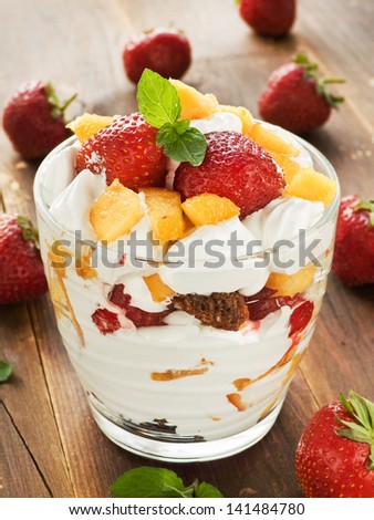 Glass with strawberry-peach parfait and whipped cream. Shallow dof.