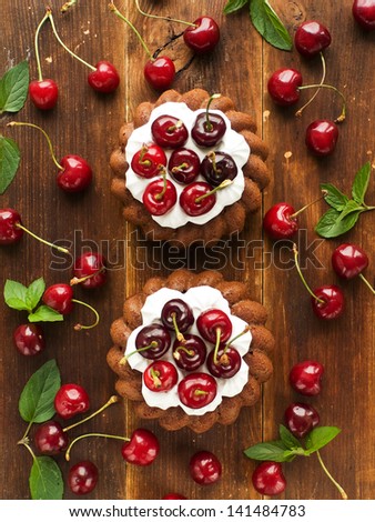 Coconut cakes with whipped cream and sweet cherry. Viewed from above.