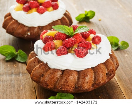 Coconut cakes with whipped cream, peach and wild strawberries. Shallow dof.