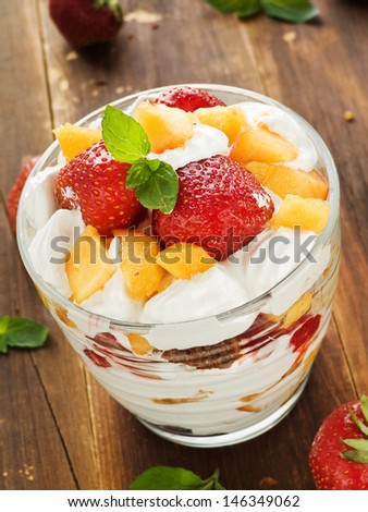 Glass with strawberry-peach parfait and whipped cream. Shallow dof.