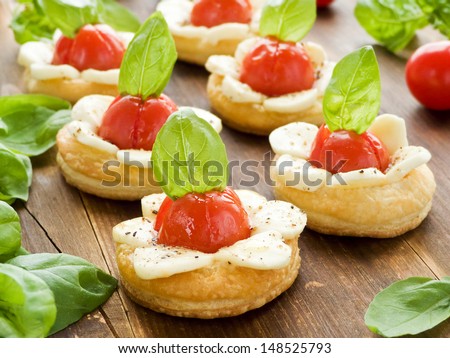 Puff-pizzas with mozzarella cheese, cherry tomatoes and baby basil. Shallow dof.