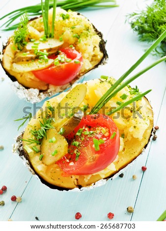 Baked potato with pickles, tomatoes and fresh greens. Shallow dof.