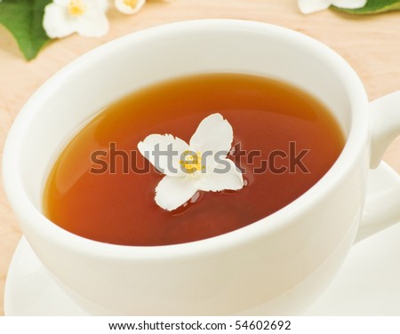 White cup with jasmine tea and blossom. Shallow dof.