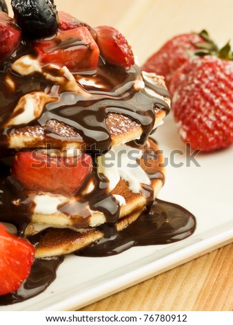 Pancakes with berries, whipped sour cream and chocolate topping. Shallow dof.