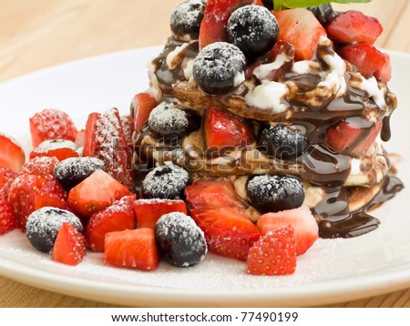 Pancakes with berries, whipped sour cream and chocolate topping. Shallow dof.