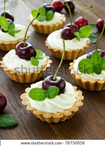 Tartlets with sweet cherries, whipped sour cream and mint. Shallow dof.
