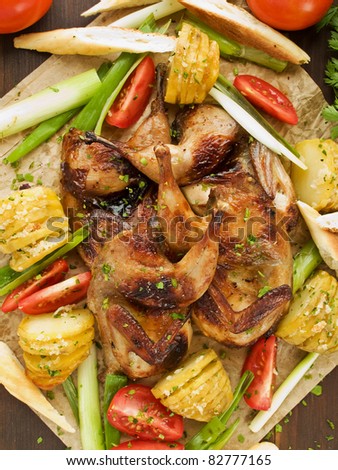 Roasted quails, baked potatoes and fresh vegetables. Viewed from above.