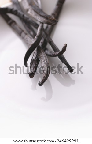 VANILLA PODS 3 - A close up of vanilla pods on a white plate with shallow depth of field