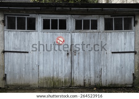 Garage with weathered white doors in Beaulieu-sur-Dordogne. No parking in front.