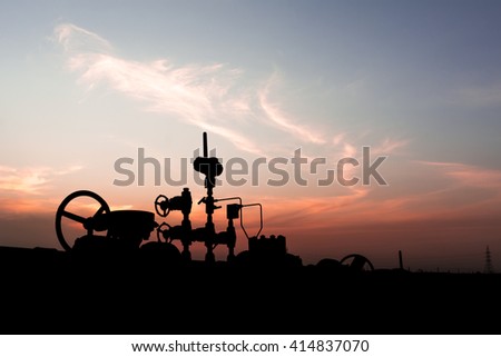 Sunset and Silhouette of wellhead controls in oilfield