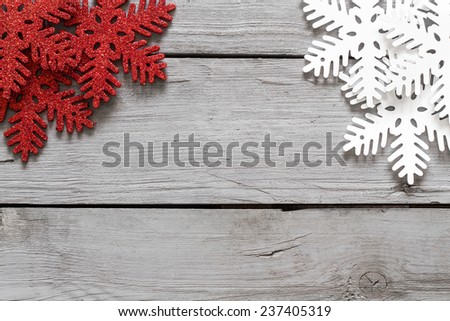 Red and white snowflakes hanging from the top corner of a wooden table. Ideal for backgrounds or gift cards.