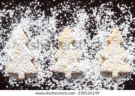 Homemade christmas cookies with powdered sugar on a black background, top view.