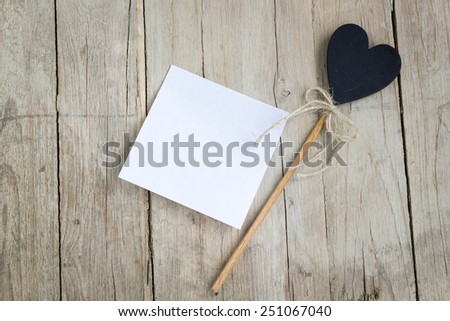 Empty white paper with heart-shaped decoration on a wooden table for any kind of notes or messages.