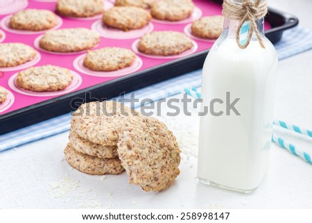 Almond and coconut cookies with a bottle of milk and straws. Cookies in the baking pan in the background.