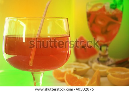 red cocktail with another  cocktail glass blur in the background and orange sections