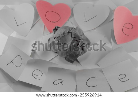 Love and peace written on post it notes with a screwed up peice of paper with war written on it, symbolising, peace and love conquering war, some images with colour removed to certain sections