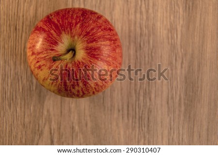 Apple shown on a wooden background .
