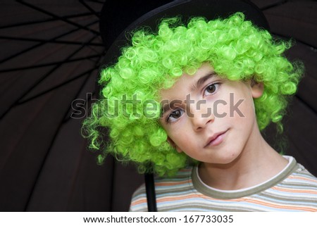 Portrait of boy with umbrella green wig and looking at camera