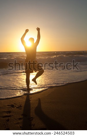 Silhouette of man on sunset with hand up