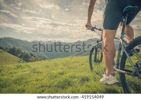 Young athletic man riding bike in sunny day in mountain