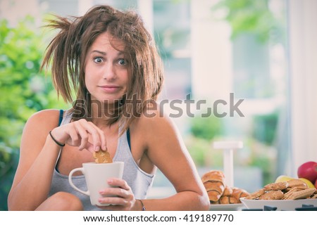 Young messy woman have breakfast in the kitchen