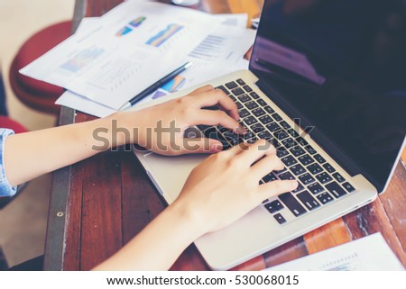 Young business woman working on laptop computer while sitting in vintage cafe bar.