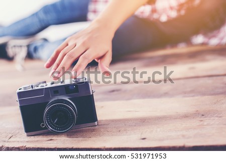 Young hipster woman hand reach out for catch retro camera.