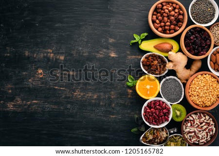 Various superfoods. Dried fruits, nuts, beans, fruits and vegetables. On a black wooden background. Top view. Free copy space.