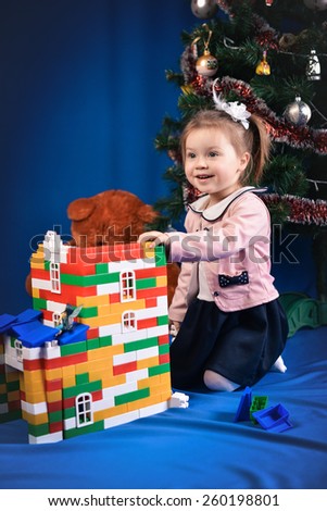 surprised little girl in purple jacket with toys on a blue background