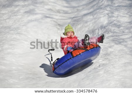 A little girl up in the air on a tube sledding in the snow