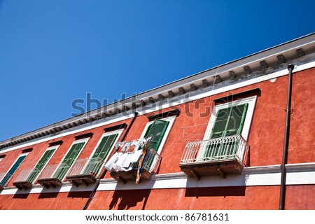 Detail of an ancient red house with a blue sky background in Procida Isle, Italy