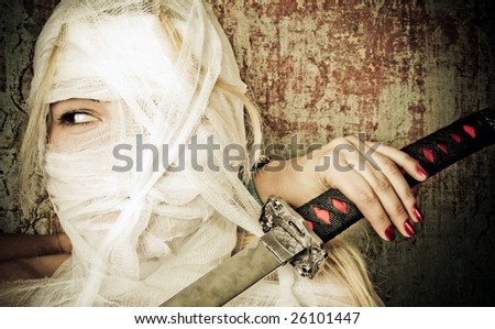 Woman in bandage on the dirty background with a japanese sword
