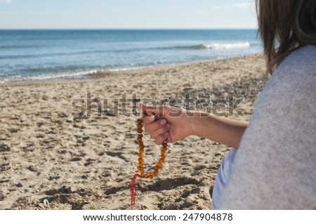 girl with beads in his hands sitting on the sea shore