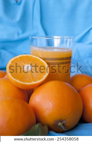 ripe orange fruits in the basket and a glass of freshly squeezed juice