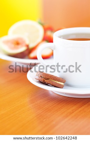 cup of tea,cookie, lemon, fig and strawberries on a plate