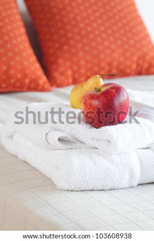 apple and pear on towels on the bed with two pillows