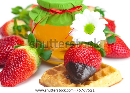 big juicy ripe strawberries in chocolate,flower, a jar of honey and waffles isolated on white