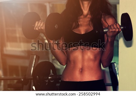 Fitness woman with dumbbells. Close-up shot of torso