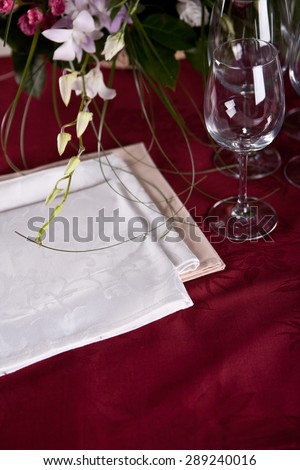 Luxury white serviettes on the red table-cloth with flowers